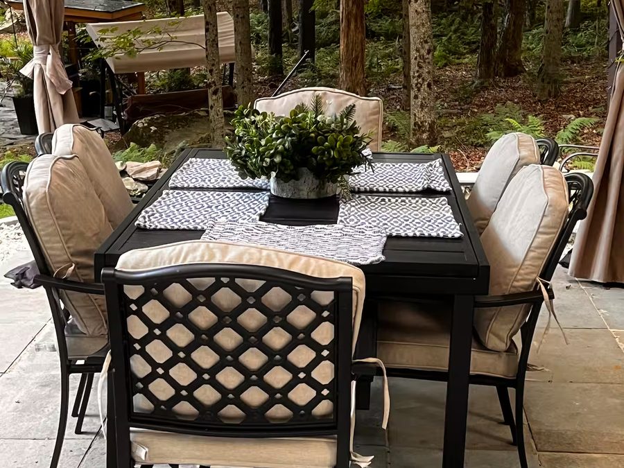 Outdoor dining table set for six on the stone patio under the trees