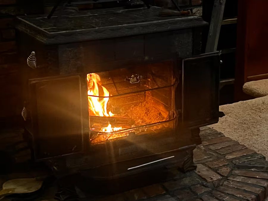 Wood-burning stove lit on the brick hearth in the living room